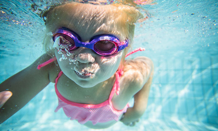 Colorful logo for Abra Cadabra Swim School featuring a cheerful, cartoon fish wearing goggles and surrounded by a blue circular background.